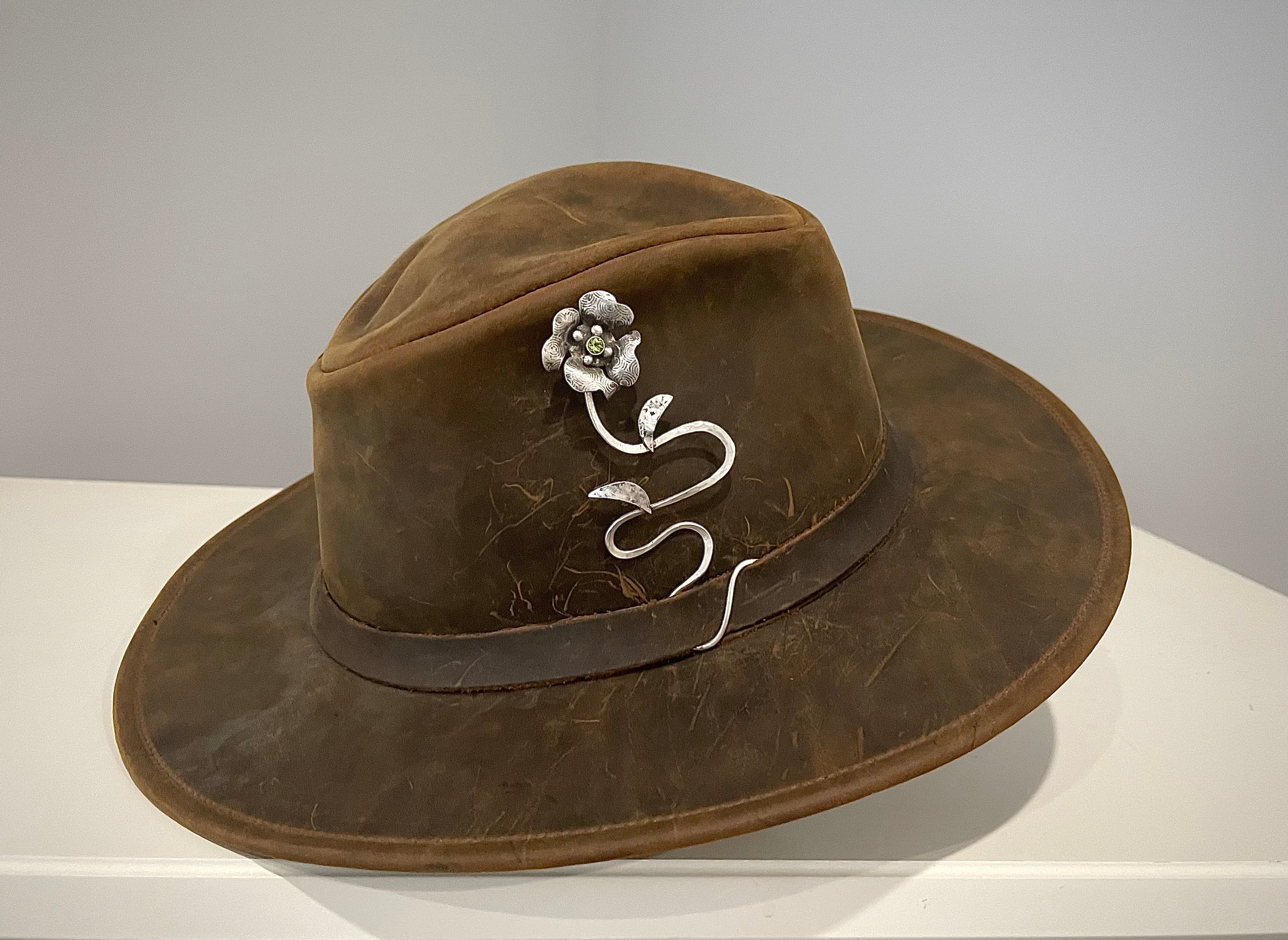 this is a sterling silver flower hat jewelry piece with a peridot