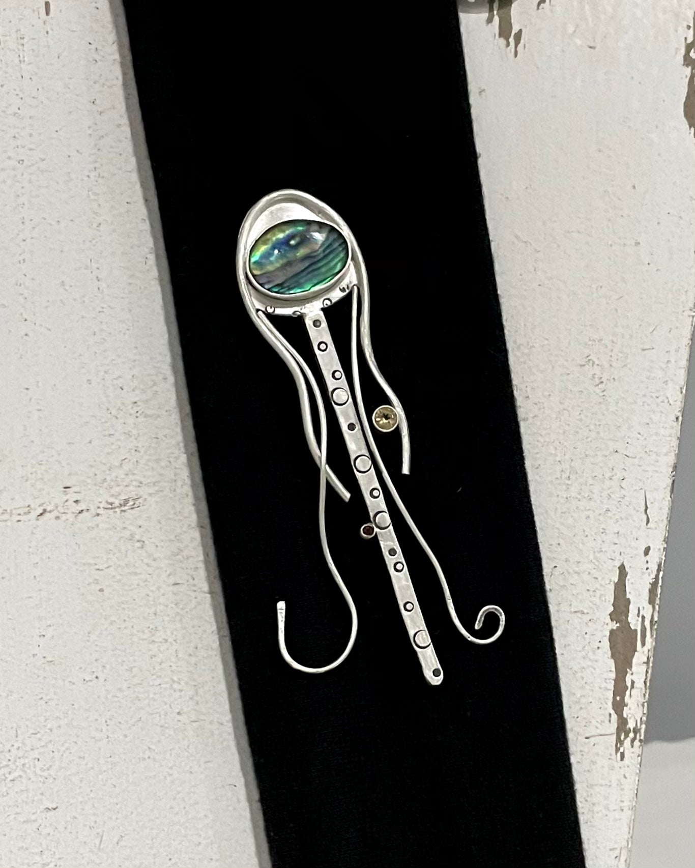 a handcrafted silver creature featuring abalone shell and small stones