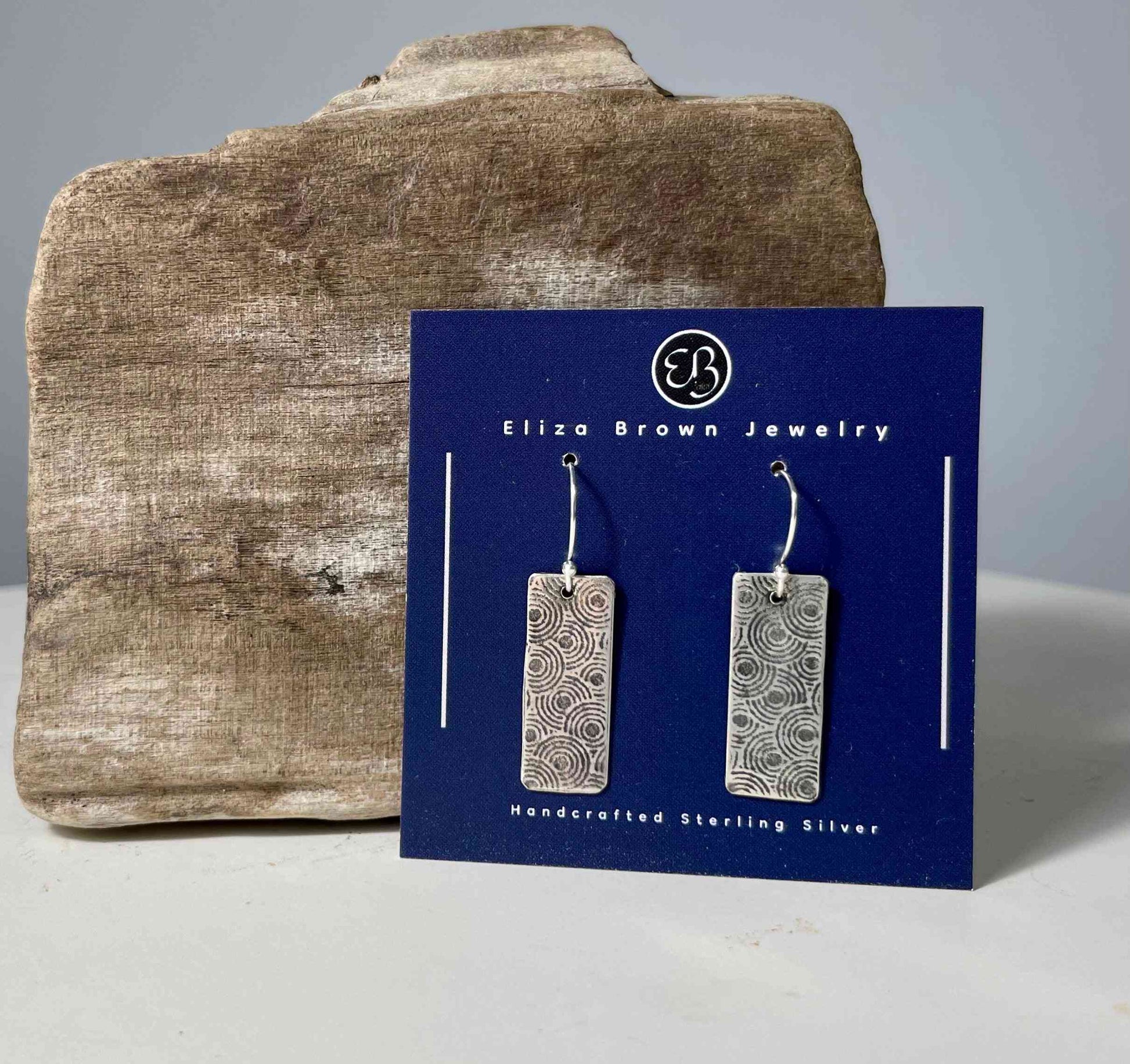 Handmade sterling silver earrings with circular etched design, displayed on branded card, part of the Circle Pattern Silver Earrings collection.