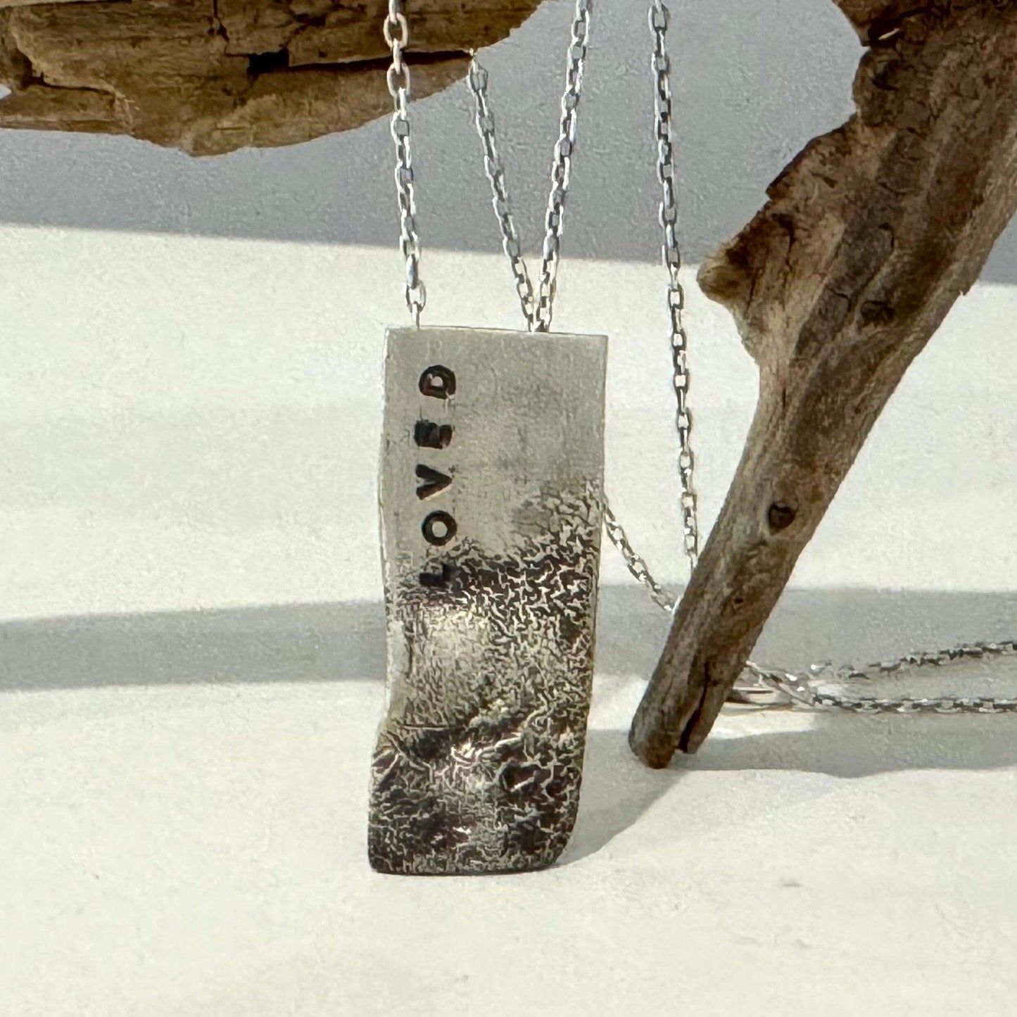 reticulated silver necklace stamped with the word loved. Rustic and handcrafted
