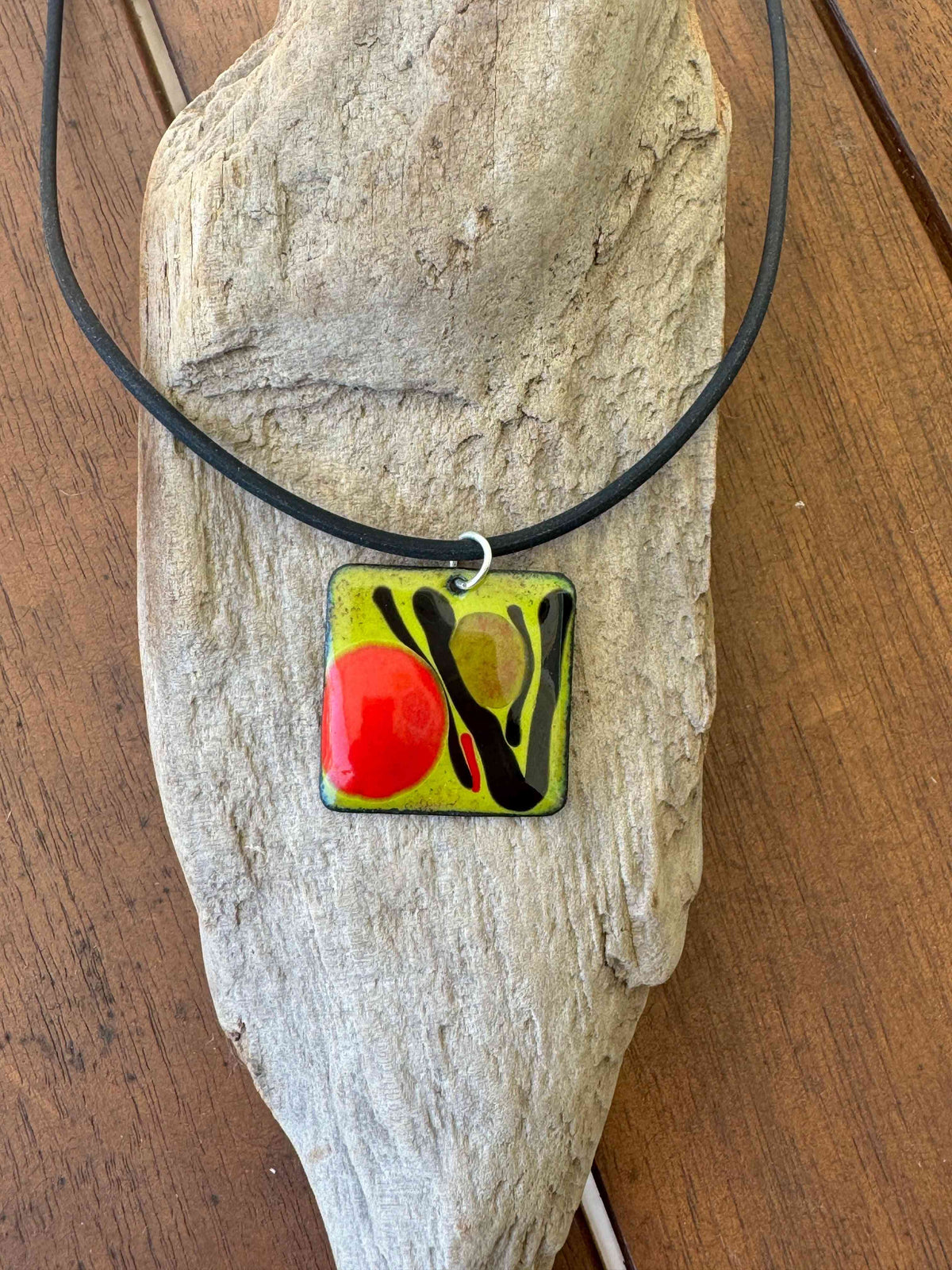 Handcrafted Abstract Enamel Necklace featuring a bold red and olive green enamel pendant with black accents on a black cord. One of a kind art jewelry.