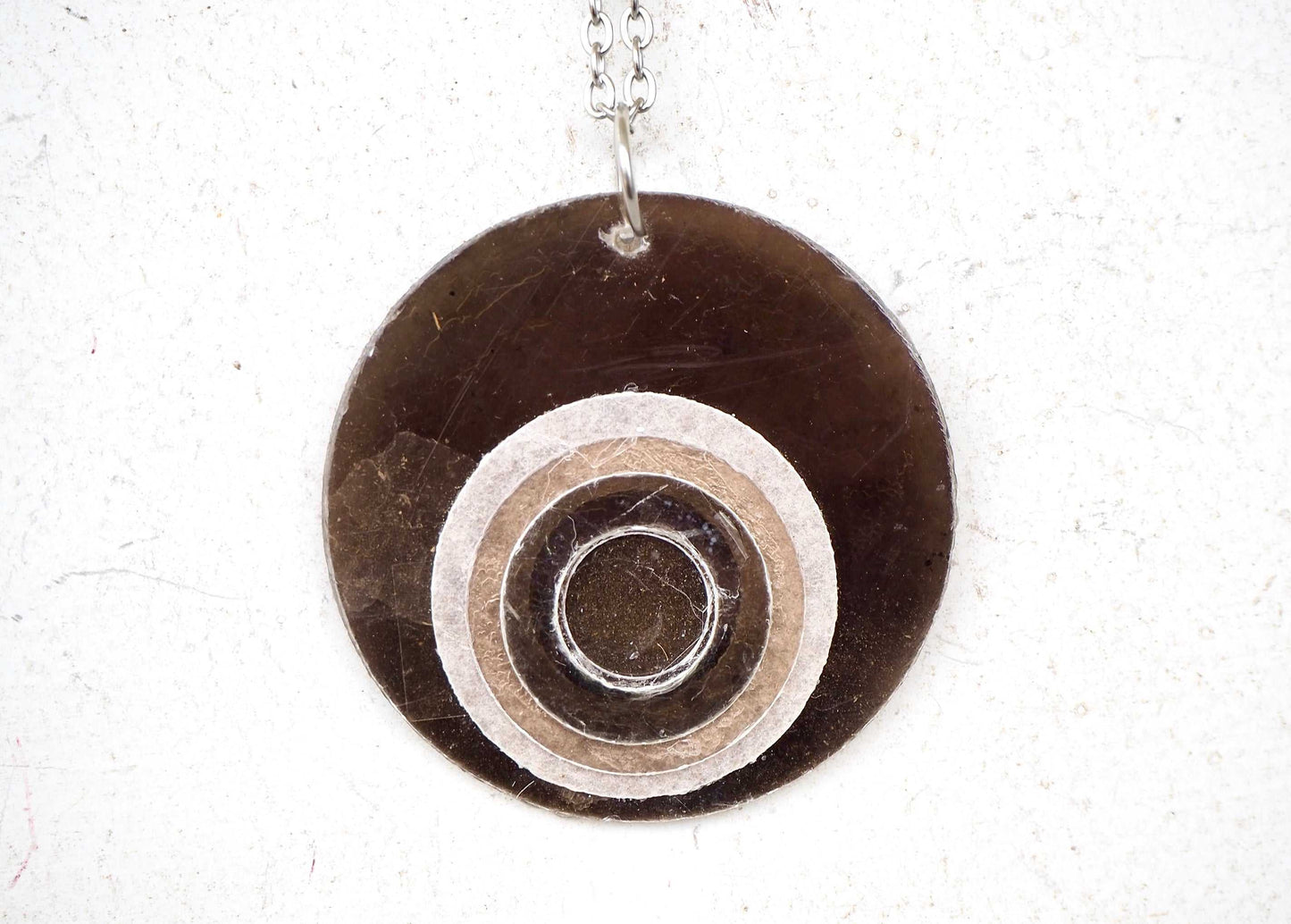 Round mica pendant with concentric circles on a white background