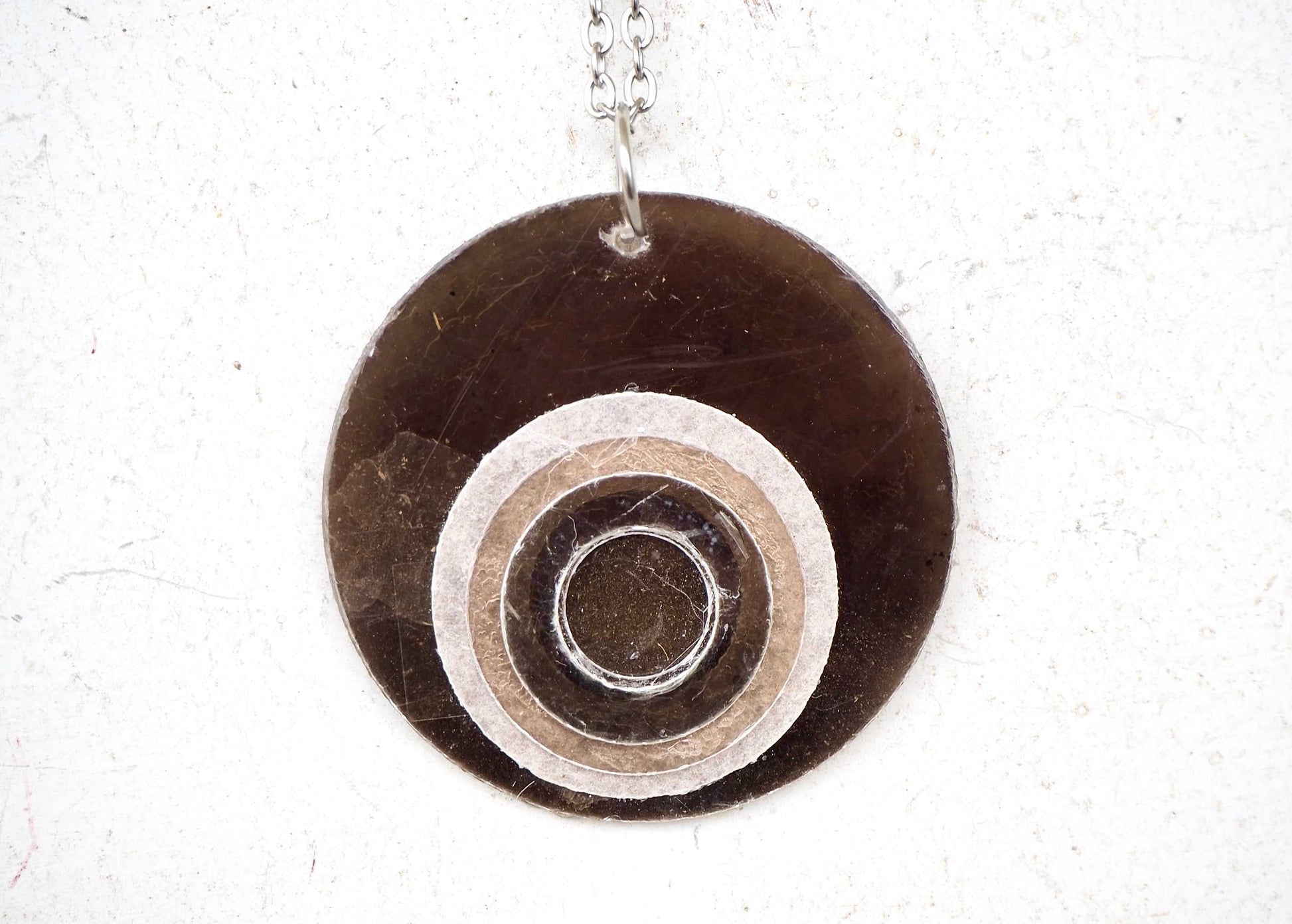 Round mica pendant with concentric circles on a white background